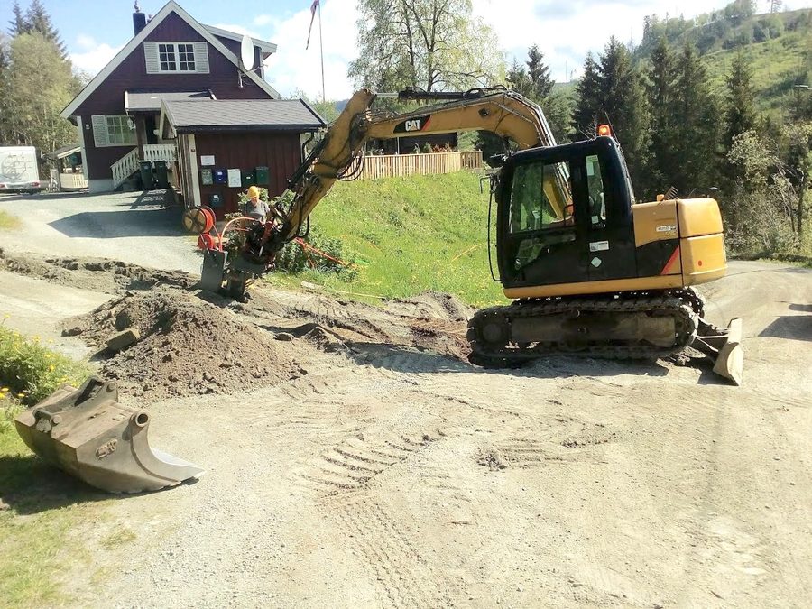 Gravemaskin ved bolig i skogkant